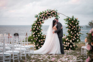 Recién casados posan frente a su ceremonia con arco floral en jardín del Hotel Nacional de Cuba
