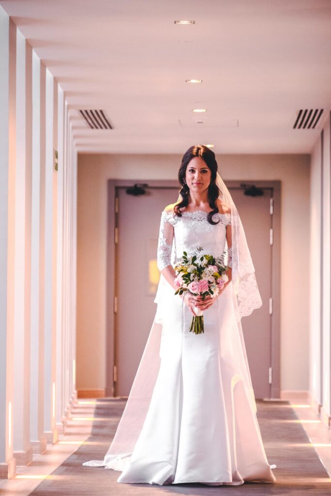 Novia con vestido blanco y ramo en pasillo del Hotel Grand Packard