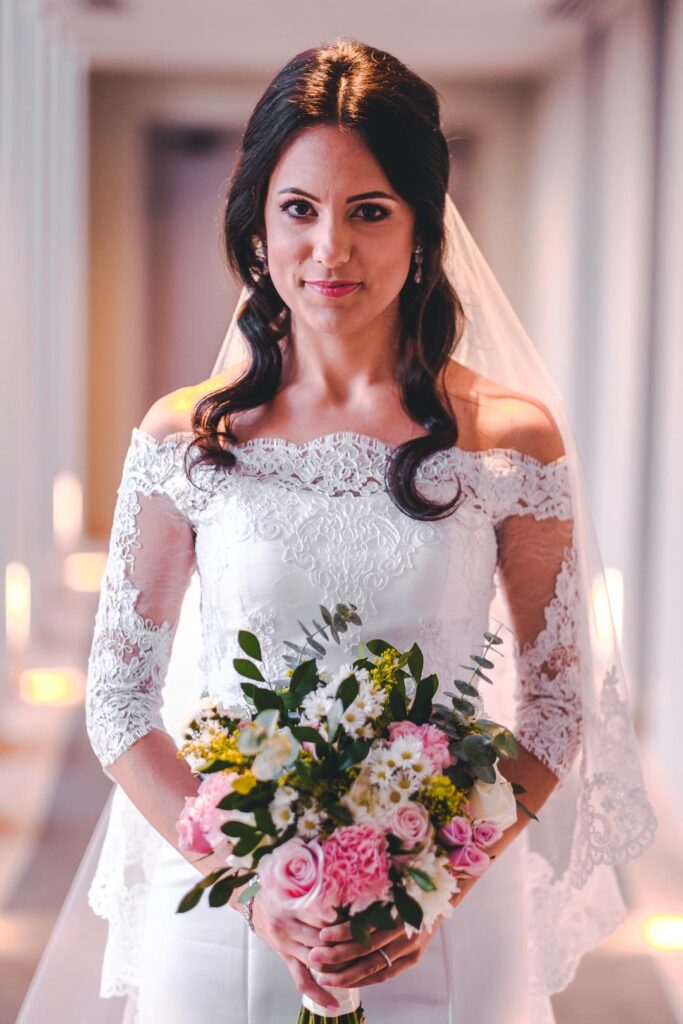 Novia con vestido de encaje y ramo colorido en el Hotel Grand Packard