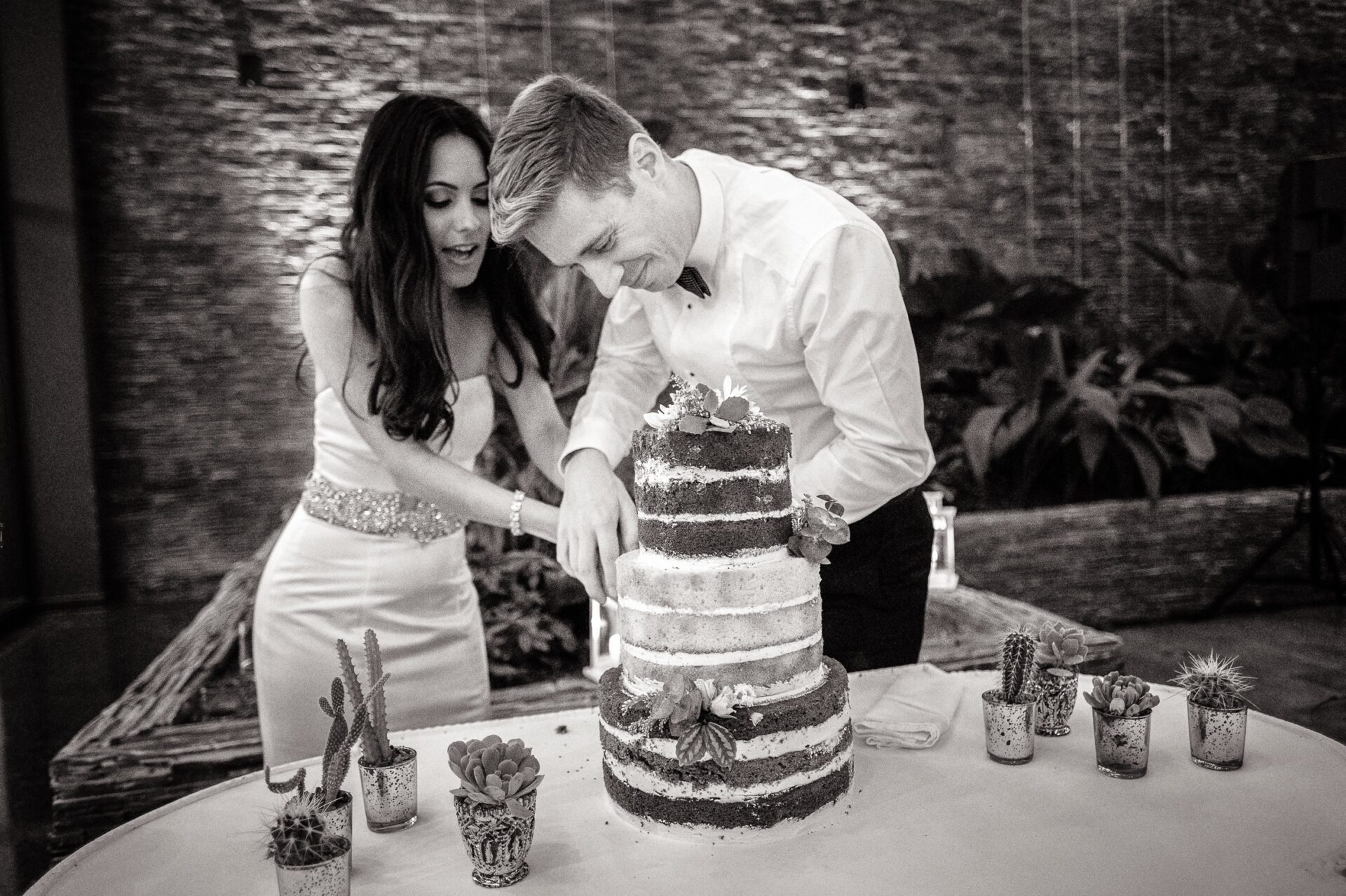 Novios cortando pastel de boda de tres pisos en el Hotel Grand Packard
