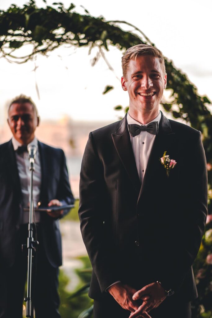 Novio sonriente frente al arco floral en el Hotel Grand Packard