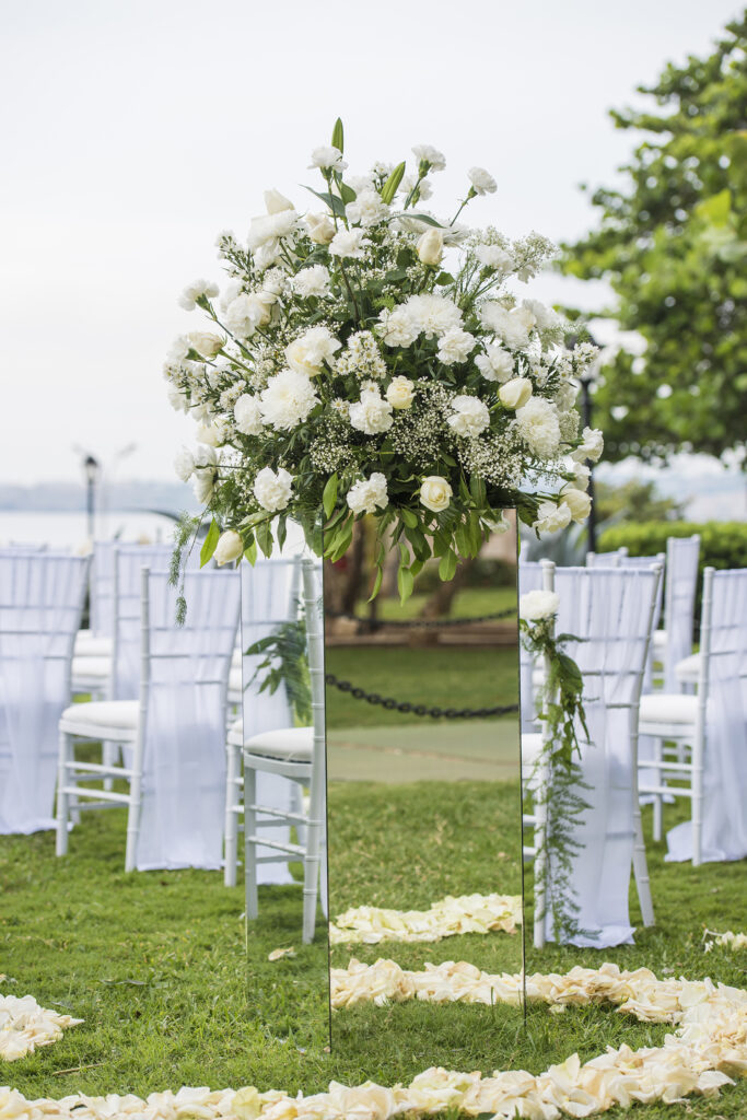 Gran arreglo floral sobre pedestal de espejo marcando la entrada a la ceremonia de boda