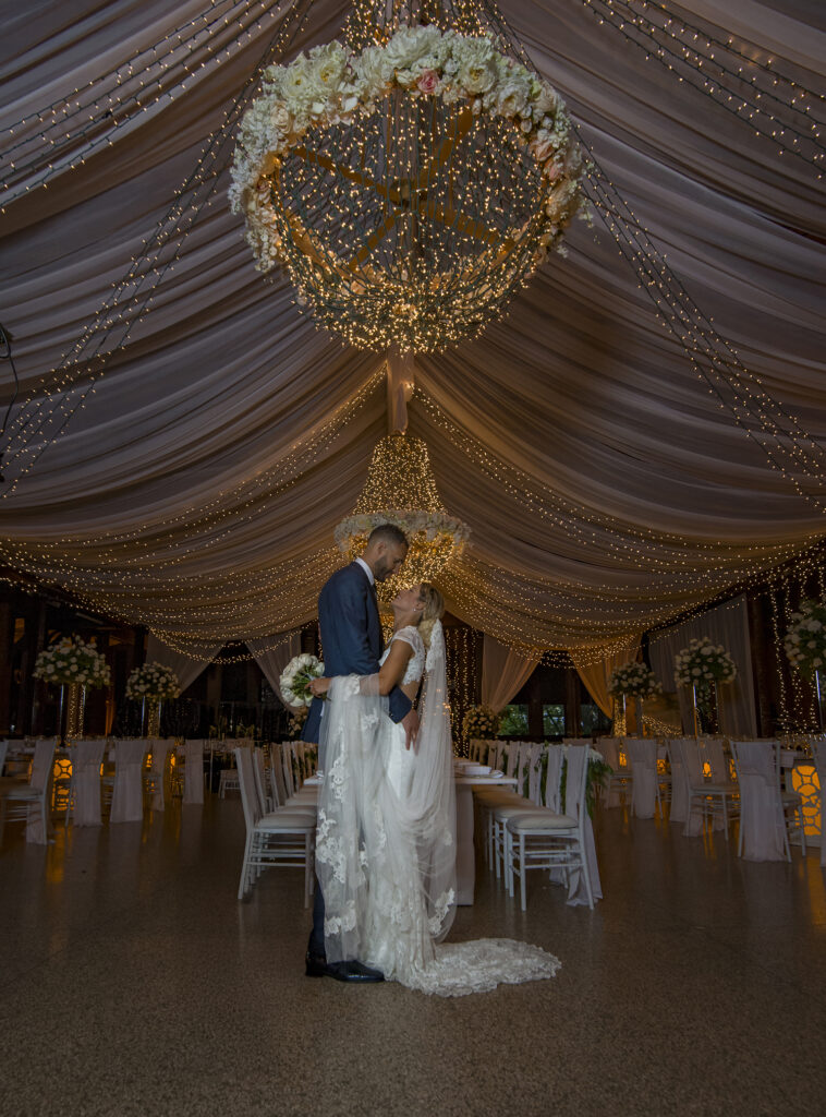 Novios en la Sala 1930 decorada con luces y telas durante su elegante boda en el Hotel Nacional de Cuba.