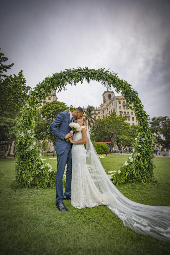 Los novios se besan frente al Hotel Nacional de Cuba, con el fondo del arco que era de follaje.