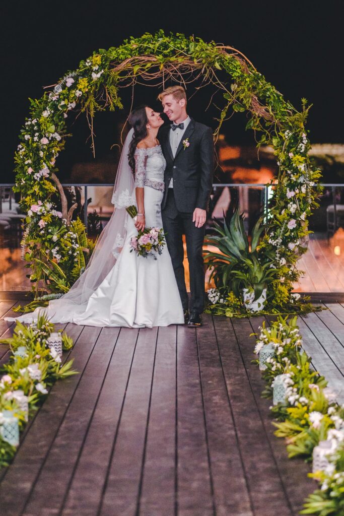 Pareja de novios posando bajo arco floral iluminado en el Hotel Packard