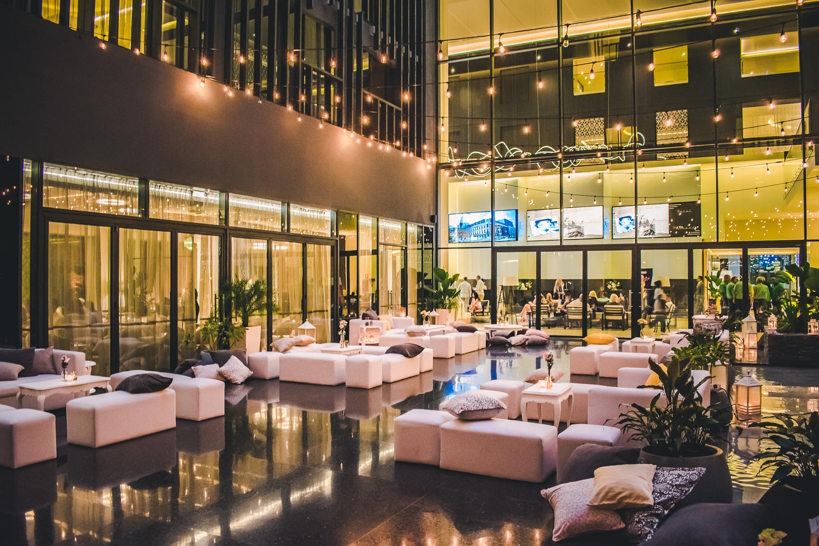 Lounge con sofás blancos, cojines y luces colgantes en el Hotel Grand Packard