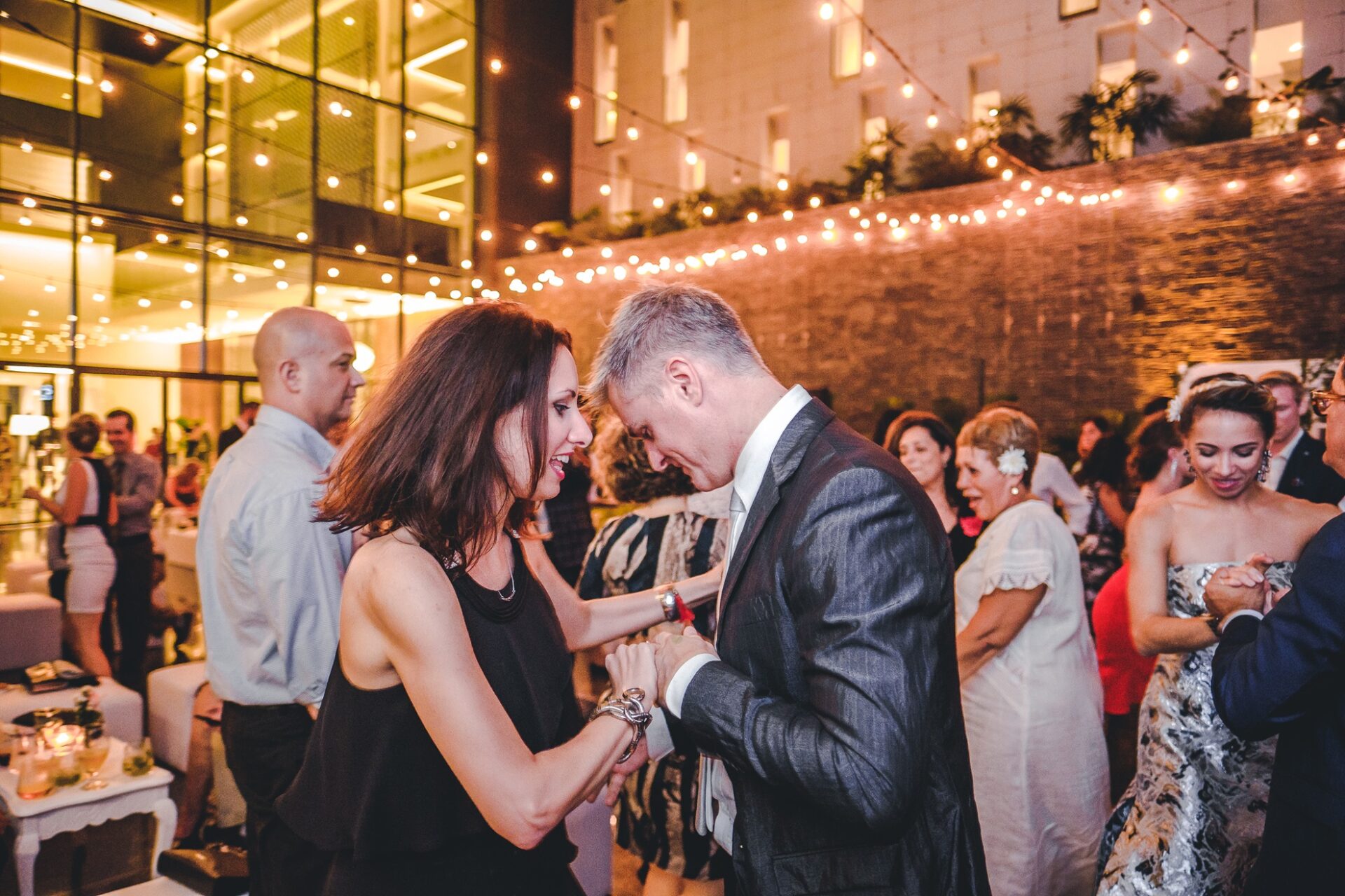 Parejas bailando en la recepción del Hotel Grand Packard bajo luces colgantes