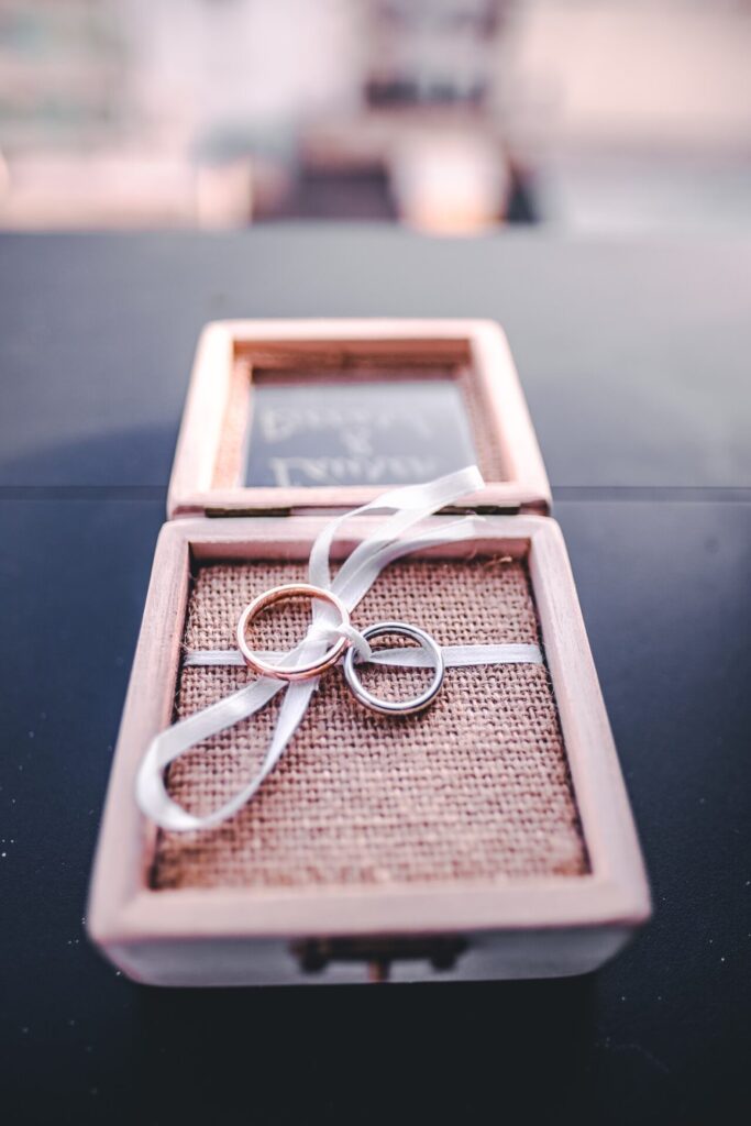 Caja de madera con anillos de boda sujetos con cinta blanca