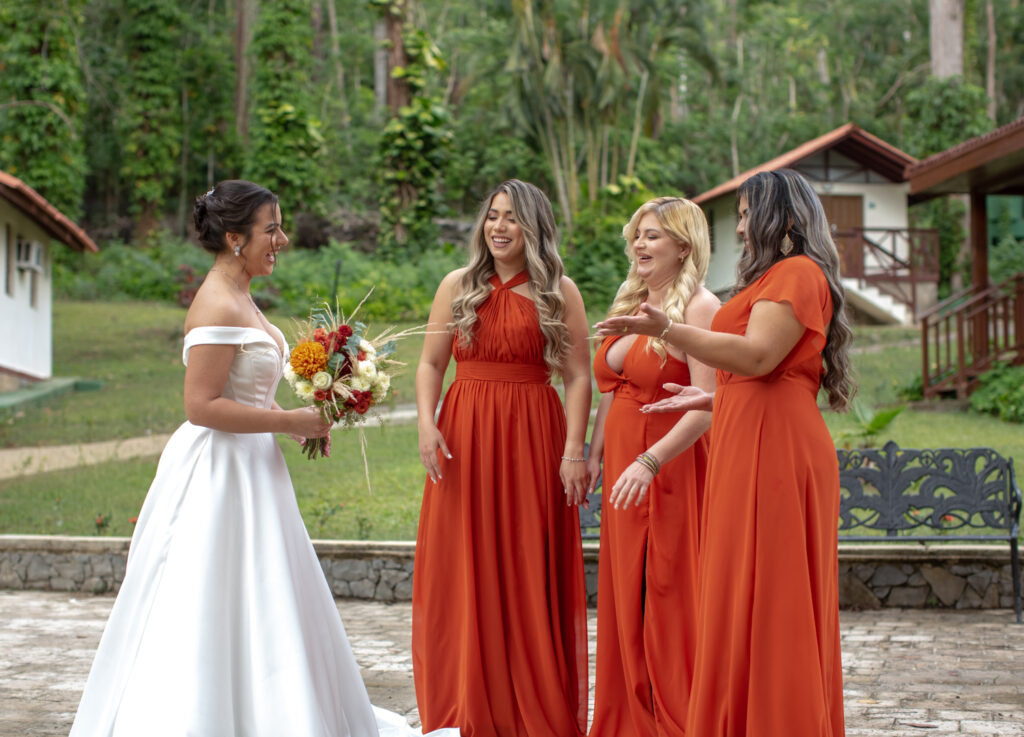 Novia sonríe con sus damas de honor vestidas de naranja en Viñales