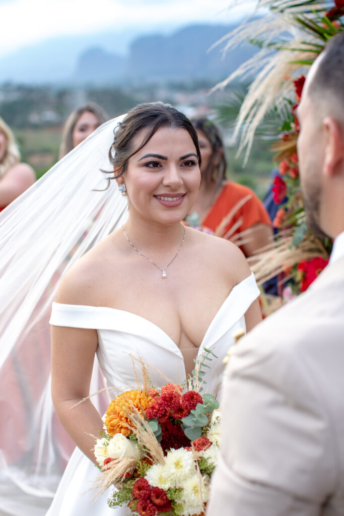 Novia sonriente sosteniendo su ramo durante la ceremonia de boda en Viñales