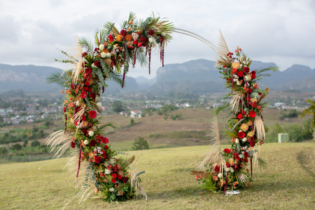 Arco circular decorado con flores rojas y pampas en boda en Viñales
