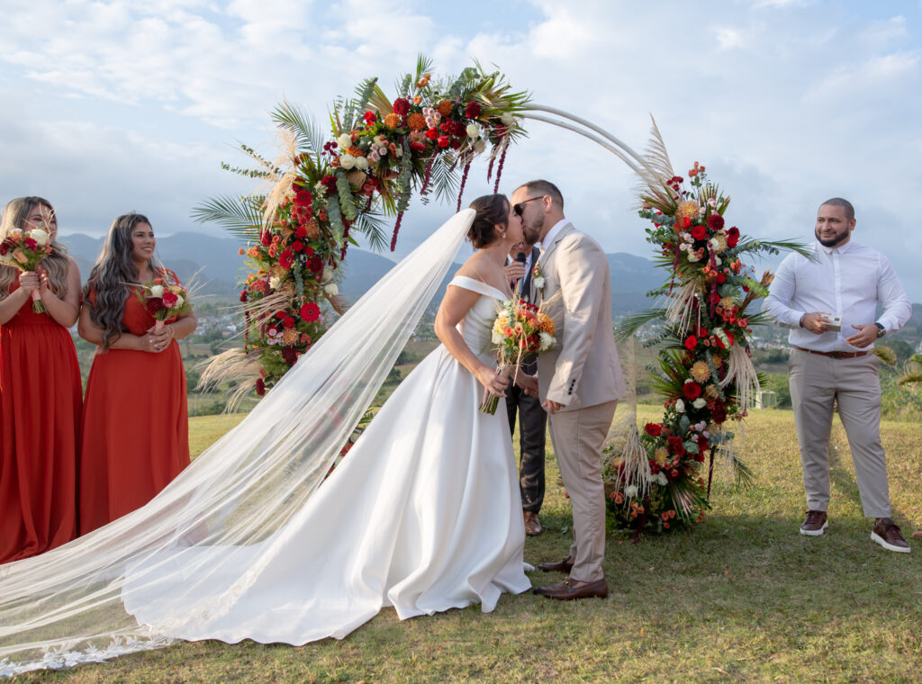 Novios sellando su boda en Viñales con un beso bajo un arco floral