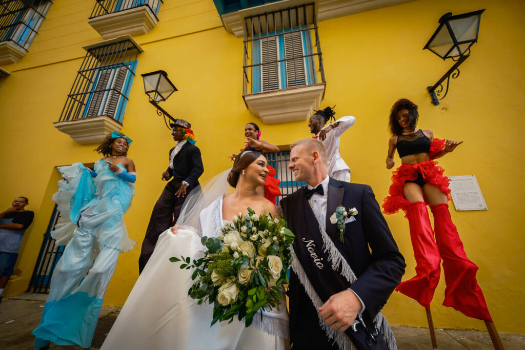 Mabel y John celebrando su boda en La Habana Vieja junto a zancos y personajes típicos