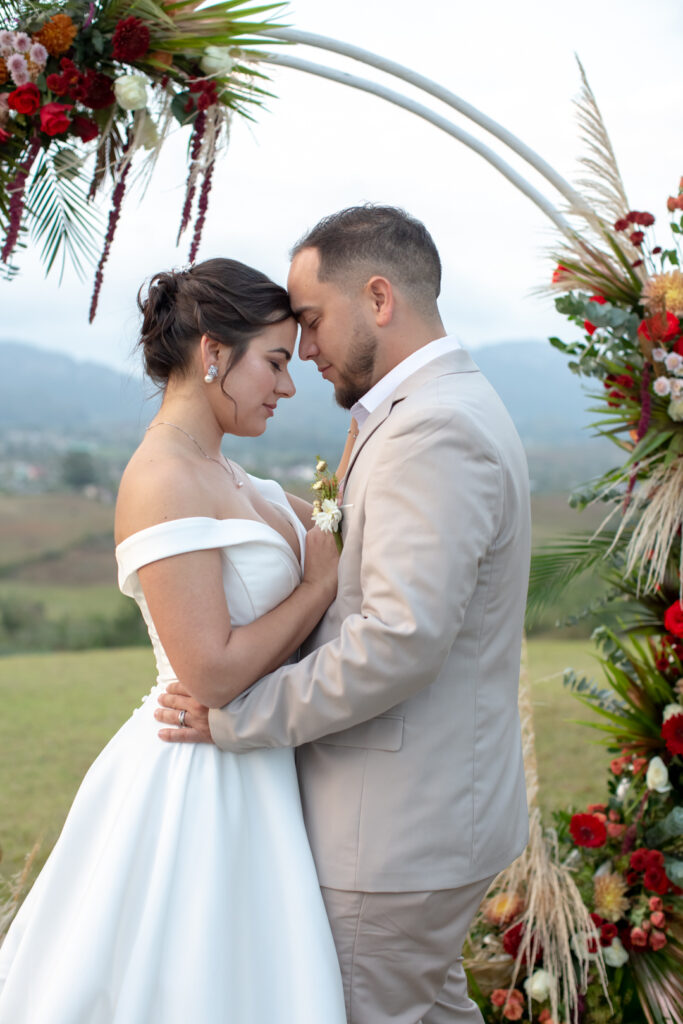Novios abrazados en su boda en Viñales bajo un arco floral