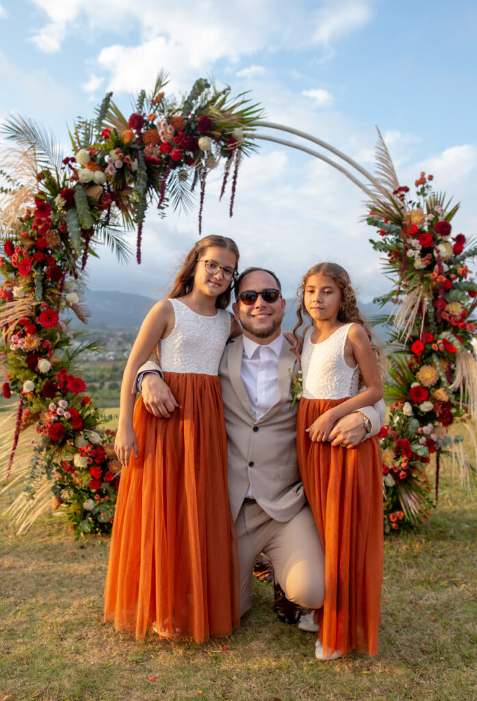 Hombre con dos niñas posando en el arco floral durante la boda en Viñales