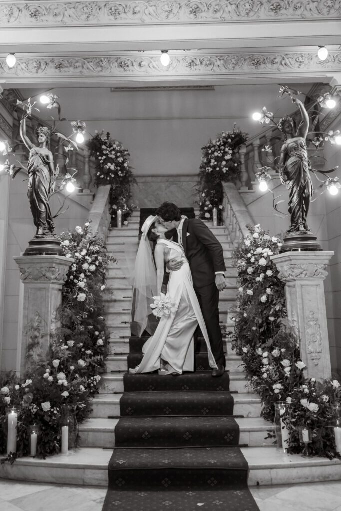 Los novios besándose en la escalera del Palacio de los Matrimonios de Prado, decorada por Aire de Fiesta.