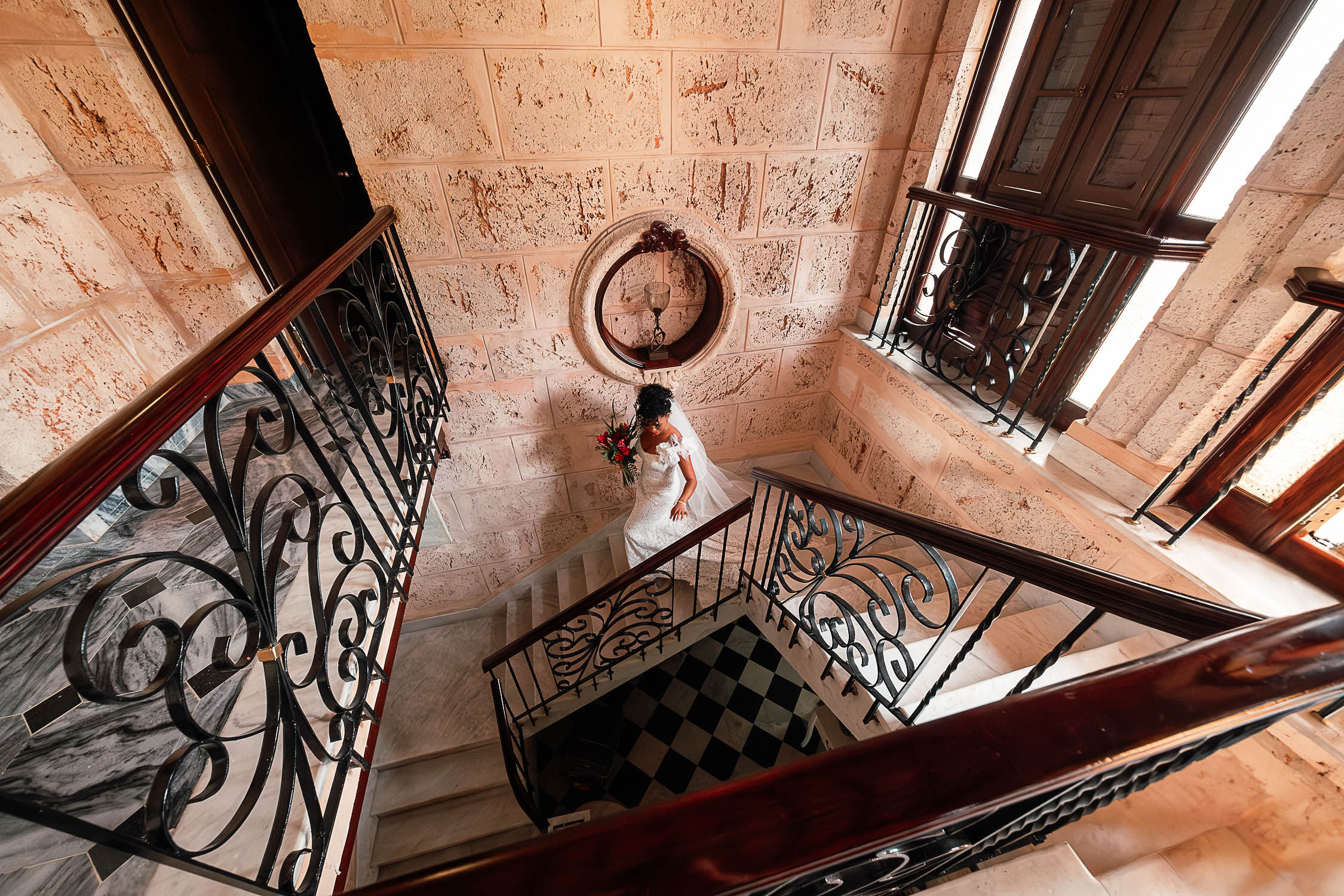 Rosmery descendiendo por unas escaleras elegantes en el lugar de los preparativos, rodeada de detalles arquitectónicos