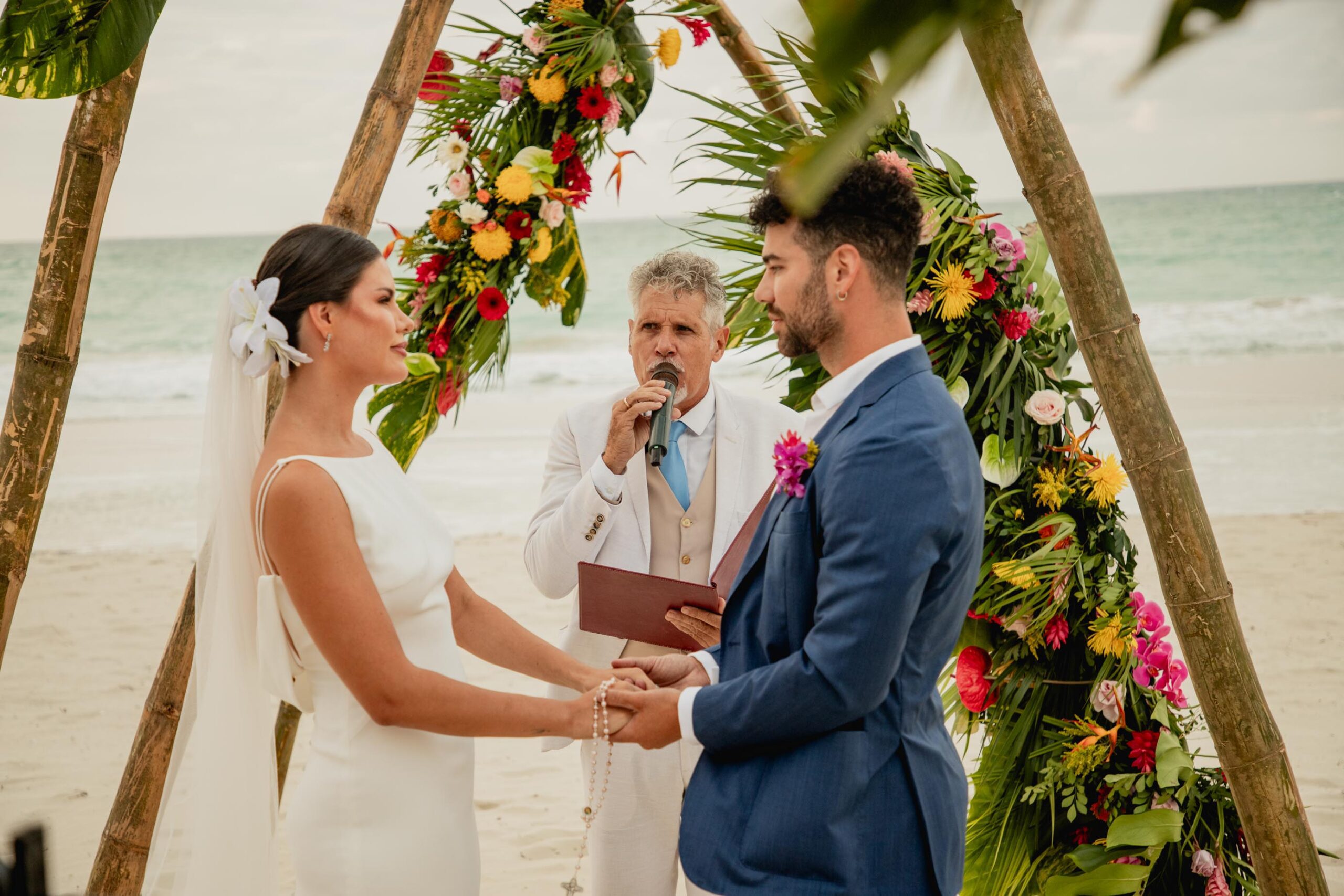 El maestro de ceremonia oficiando mientras Alba y Renato miran en el altar decorado con bambú y flores tropicales Alba y Renato