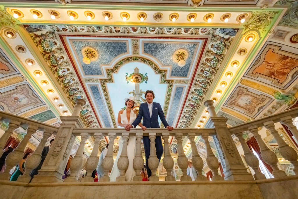 Los cónyuges en el balcón del Palacio de los Matrimonios, capturando el lujo de esta boda de destino en La Habana bajo el majestuoso techo.