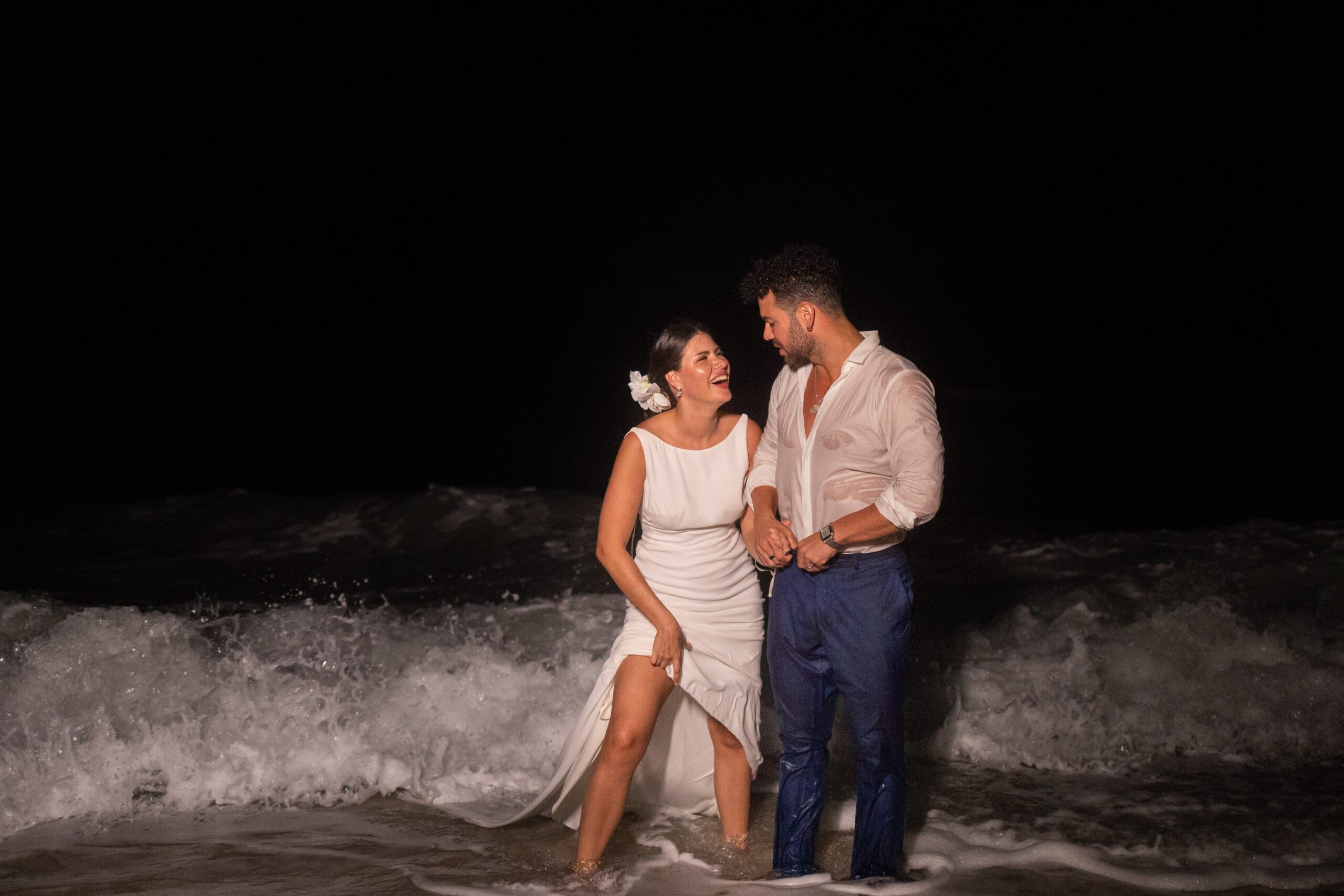 En el mar al final de la noche, ella un poco mojada y él completamente mojado en un baño de mar en su boda.