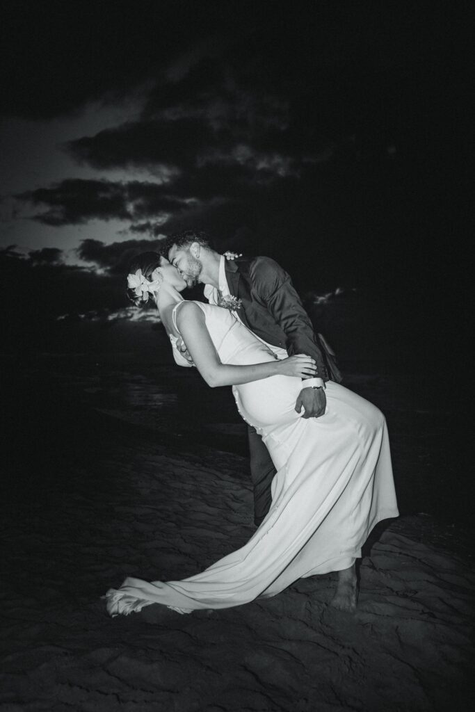 Alba y Renato besándose en la playa al anochecer, con el mar y el cielo como fondo romántico