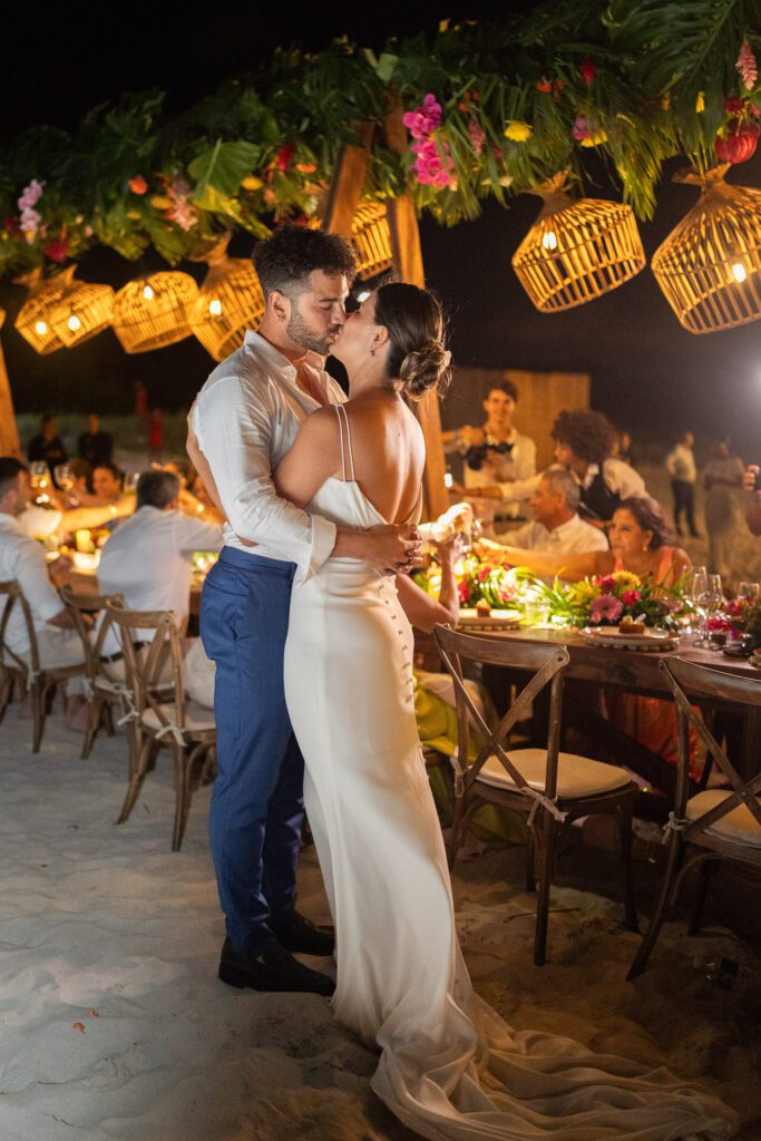 Alba y Renato compartiendo un beso junto a la mesa decorada después del brindis de bodas.