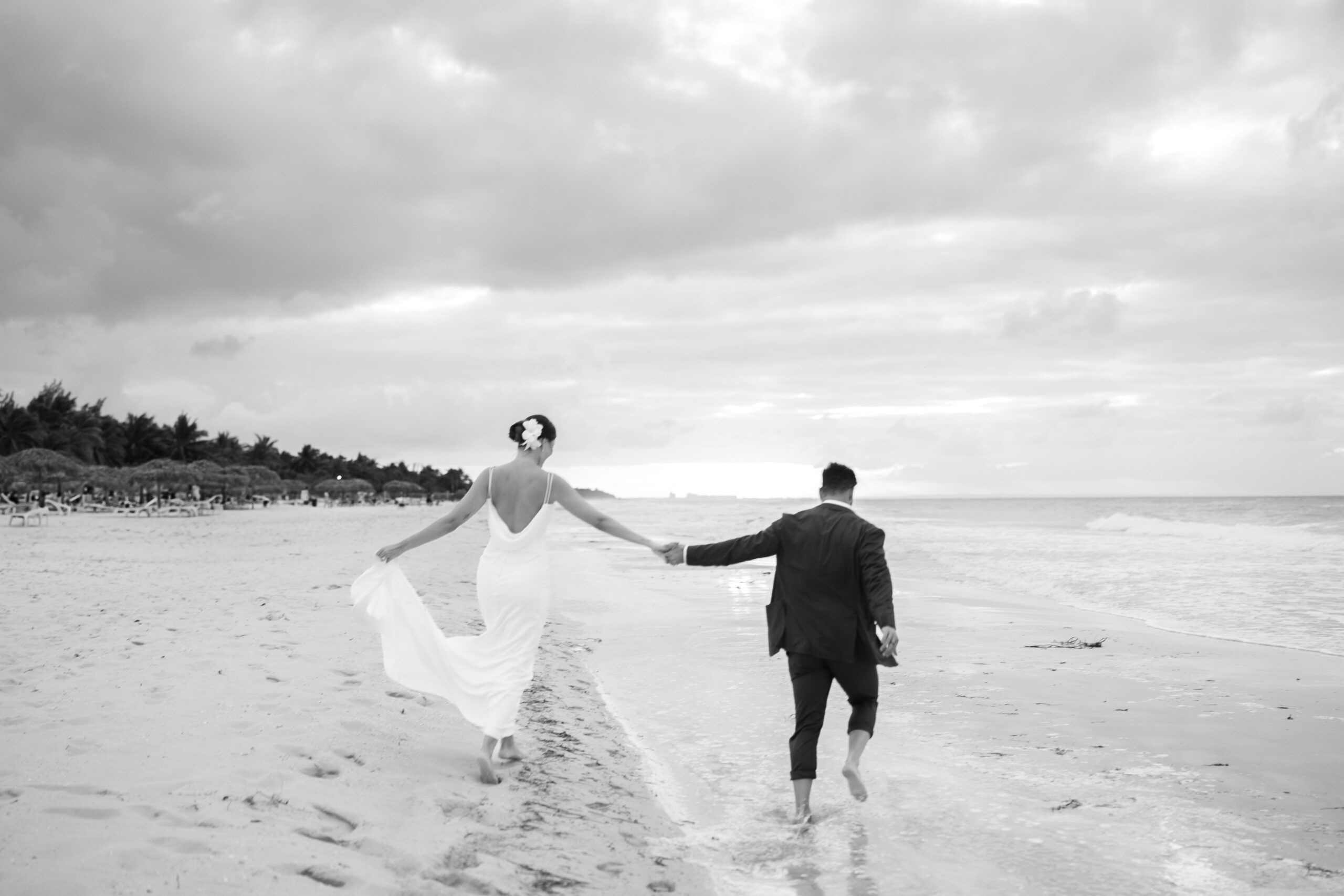 Alba y Renato caminando descalzos por la orilla del mar en Varadero después de su boda