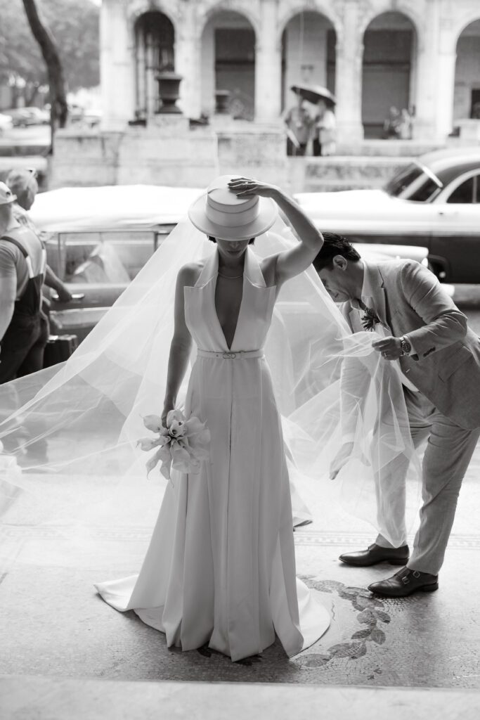 Victoria llegando al Palacio de los Matrimonios en La Habana, Cuba, con su padre acomodándole el velo antes de la ceremonia.