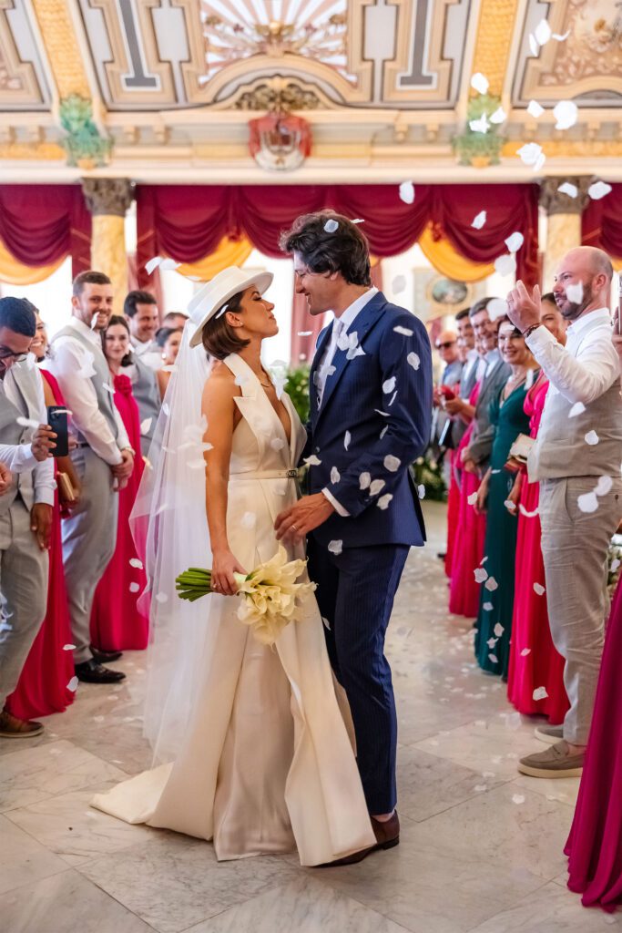 Los novios se miran tras terminar su ceremonia en el Palacio de los Matrimonios de Prado, en La Habana, Cuba, rodeados de pétalos y la celebración de los invitados.