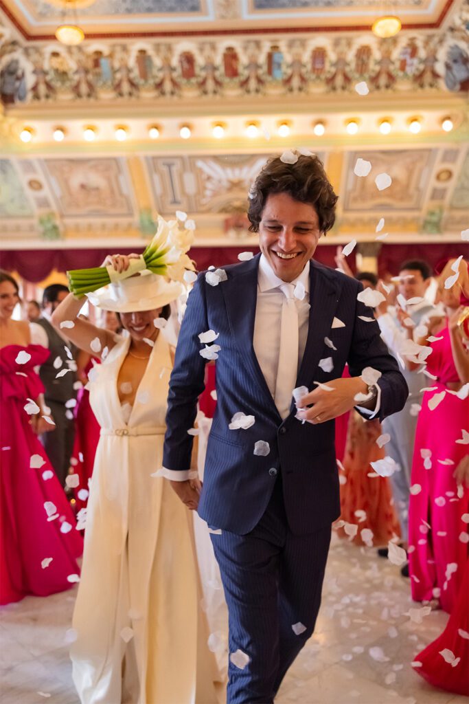 Los novios caminan riéndose bajo una lluvia de pétalos tras su boda en el Palacio de los Matrimonios de Prado, en La Habana, Cuba.”