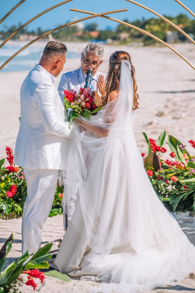 Los novios, mirando al maestro de ceremonia durante el momento clave de la boda, con el altar decorado como un fondo espectacular