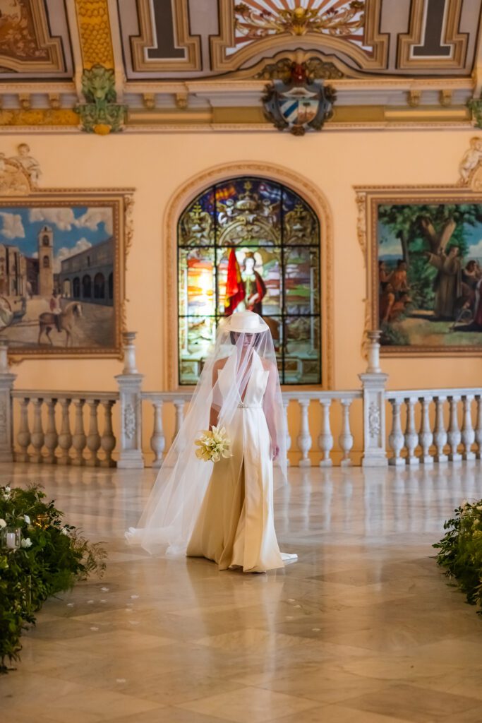 Victoria caminando sola hacia el altar en el Palacio de los Matrimonios de Prado, durante su ceremonia de boda de destino en La Habana.