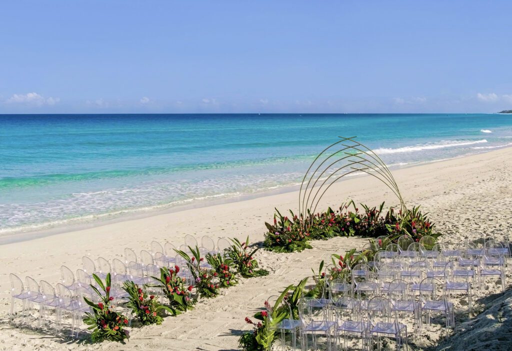 Primer plano de la ceremonia decorada con un altar moderno y tropical, diseñado con una estructura metálica dorada y un lecho adornado con flores tropicales.