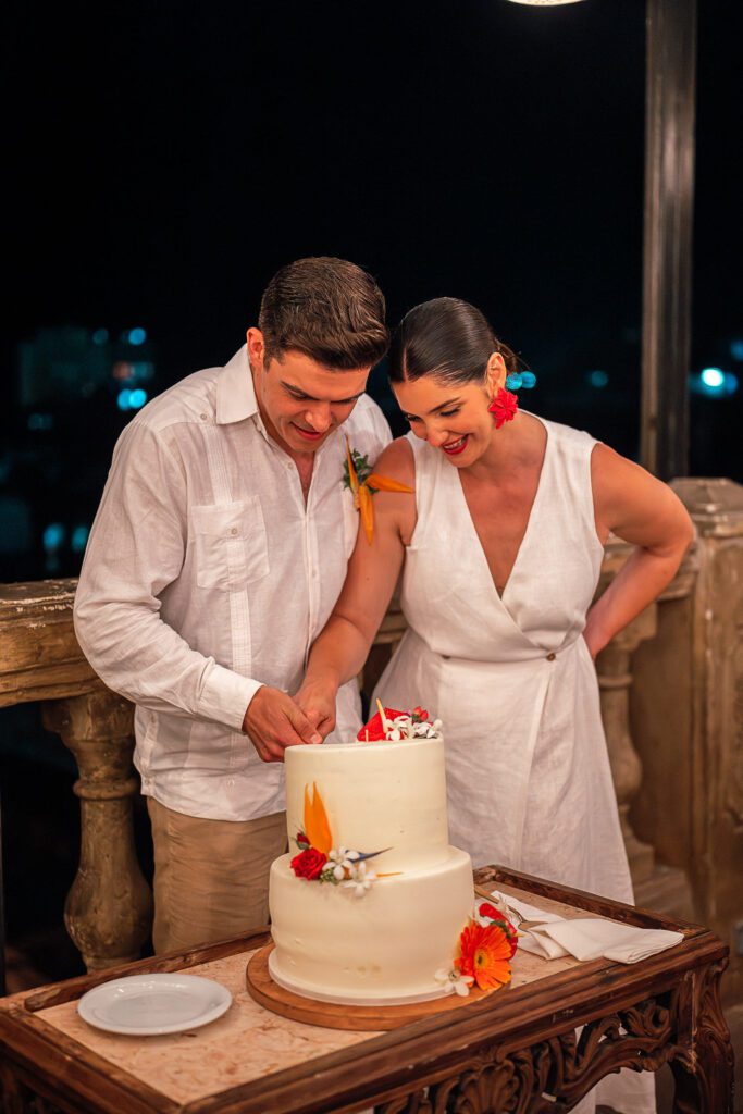 Amanda y Leo cortan el pastel de bodas en La Guarida, rodeados de una decoración tropical y la emoción de sus invitados.