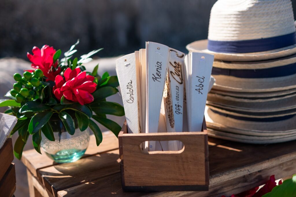 Detalle de la mesa de regalos en la boda de Giada y Gorke, con abanicos de madera y sombreros para los invitados, en Varadero.