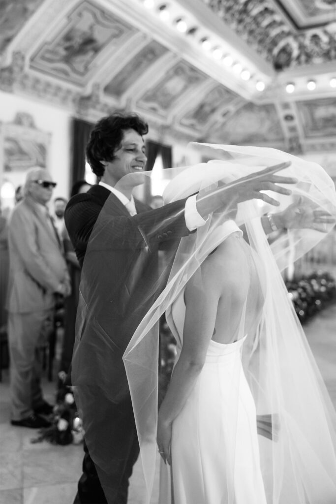 El novio levanta el velo de la novia durante su ceremonia de boda en el Palacio de los Matrimonios de Prado, en La Habana, Cuba.”