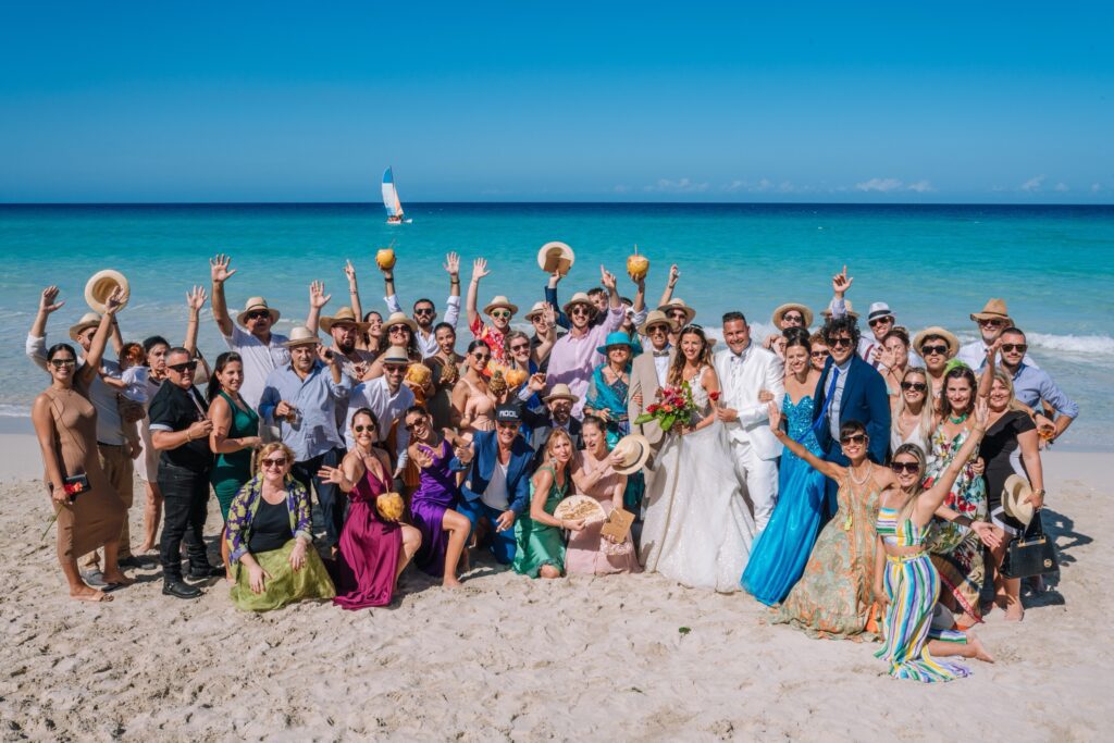 Invitados disfrutando de cócteles en cocos, con un catamarán al fondo en Varadero.