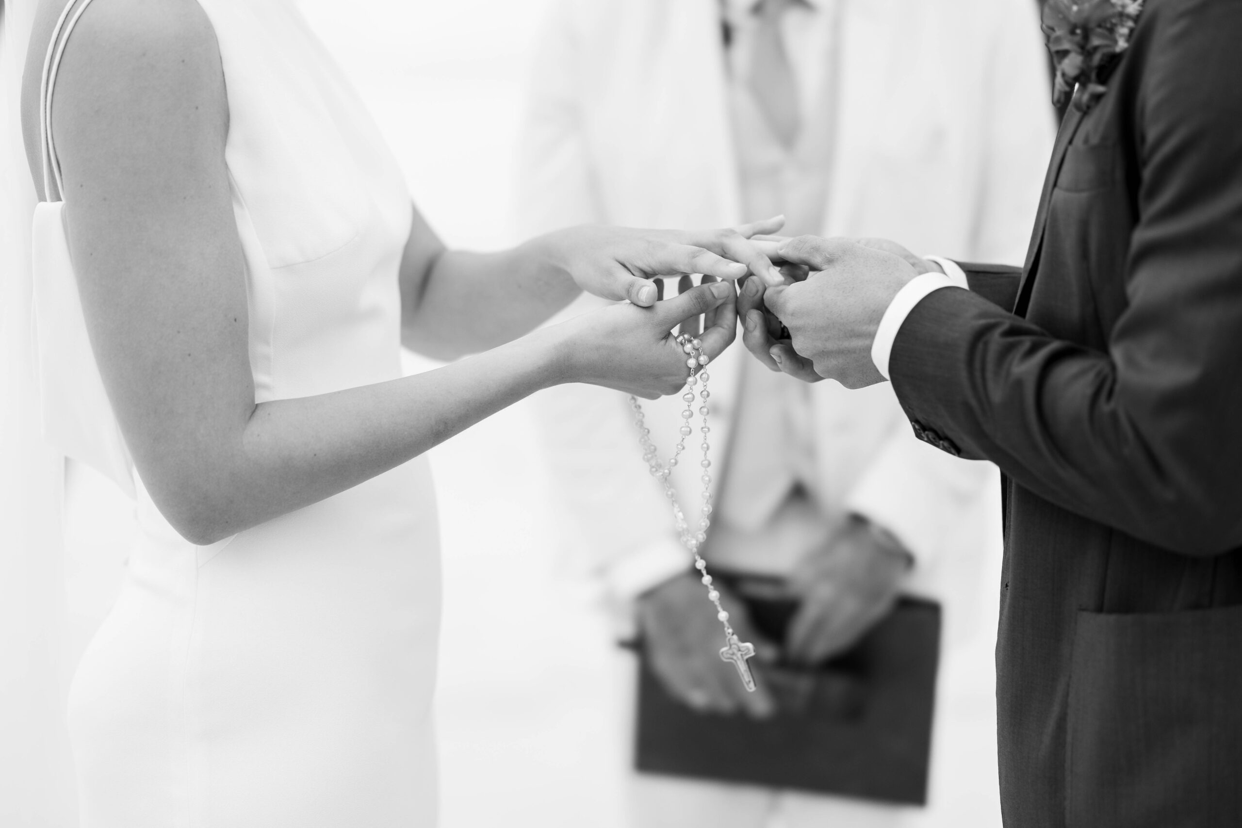 Manos entrelazadas sosteniendo el crucifijo en la boda de Alba y Renato en su boda.