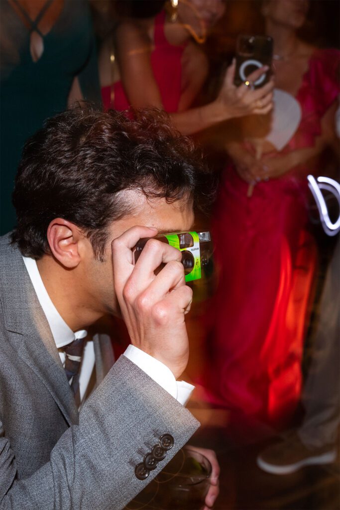 Invitado capturando momentos especiales con una cámara desechable en la boda en La Guarida, La Habana