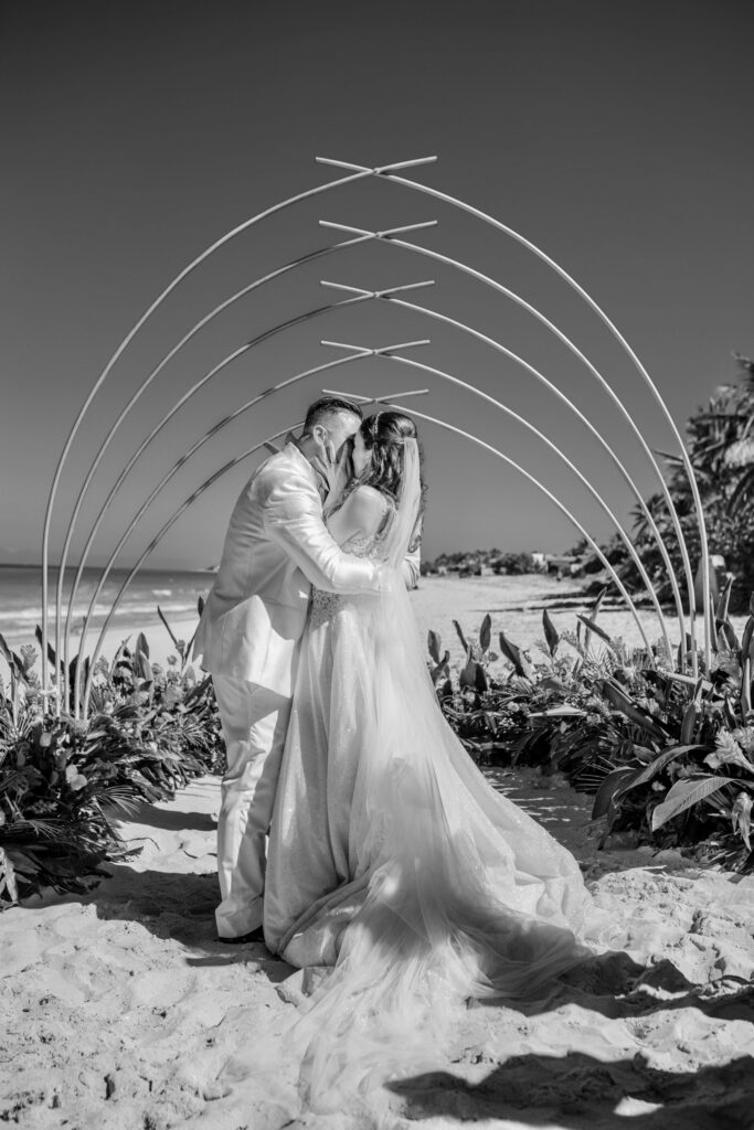 Los novios sellando su unión con un beso al final de la ceremonia, en una emotiva imagen en blanco y negro, capturada durante su boda de destino en Varadero.