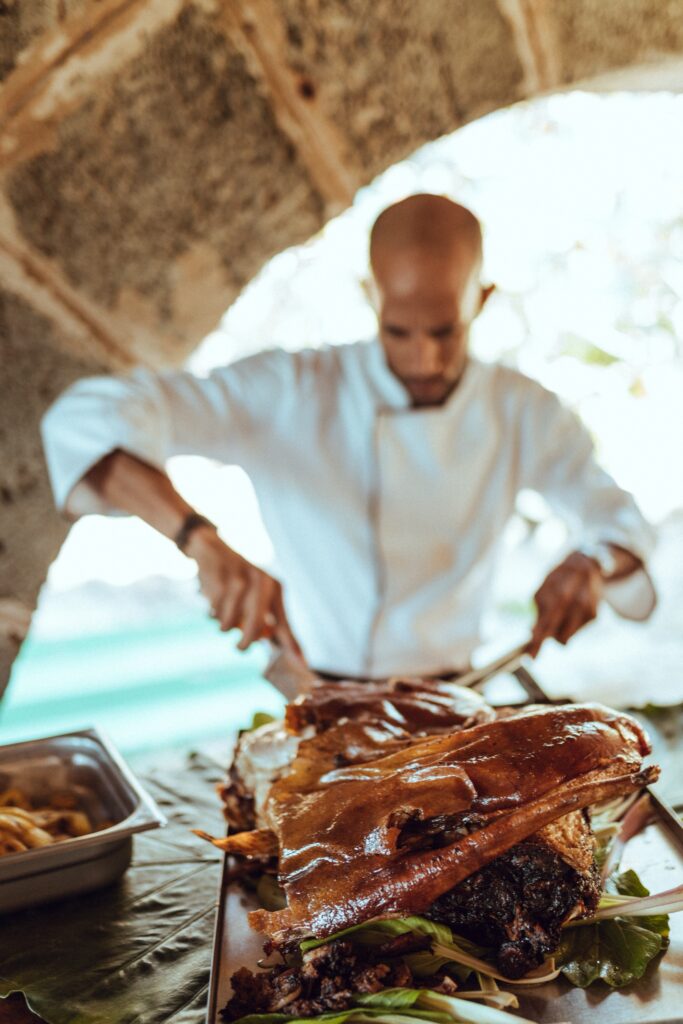 El staff del restaurante corta un lechón asado, un plato típico servido durante la boda de destino en Varadero de Giada y Gorke.