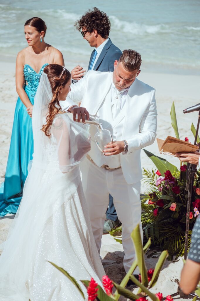 Gorke vertiendo arena de Varadero en la botella durante la Ceremonia de la Arena, un momento simbólico que representa la unión de las vidas de los novios.