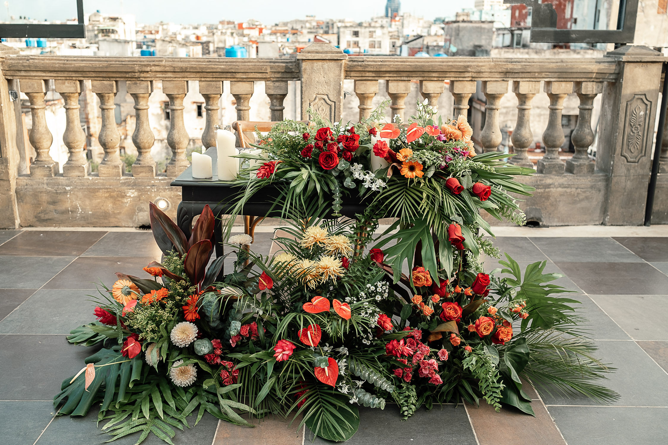 Primer plano del elegante arreglo floral en la mesa de los novios, decorada con flores tropicales y follaje, con vistas al skyline de La Habana.