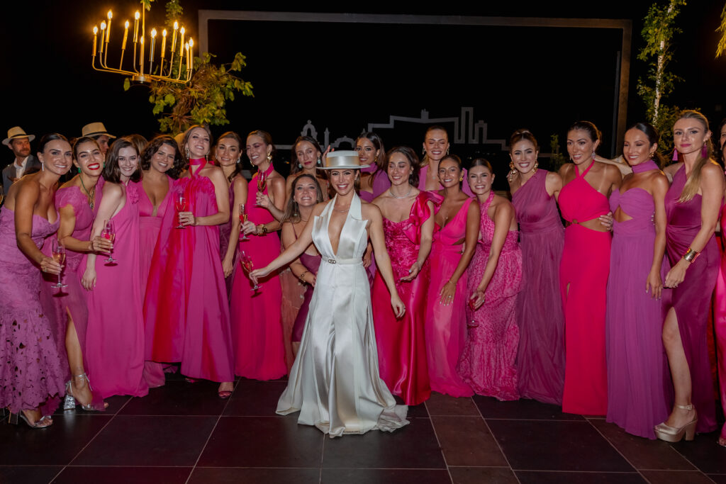 Victoria rodeada de sus damas de honor en una boda en La Guarida, La Habana, luciendo una paleta vibrante de colores fucsias y rojos.