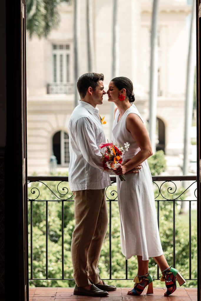 Amanda y Leo se miran enamorados en el balcón del lugar de los preparativos con la icónica vista al Capitolio de La Habana.