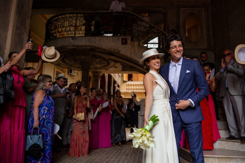 Novios sonrientes en la entrada de La Guarida, rodeados de invitados, reflejando la alegría de su boda de destino en La Habana.