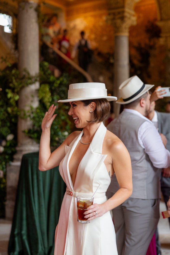 Victoria luciendo un sombrero elegante en La Guarida y disfrutando el tiempo de cóctel durante su boda de destino en La Habana, Cuba