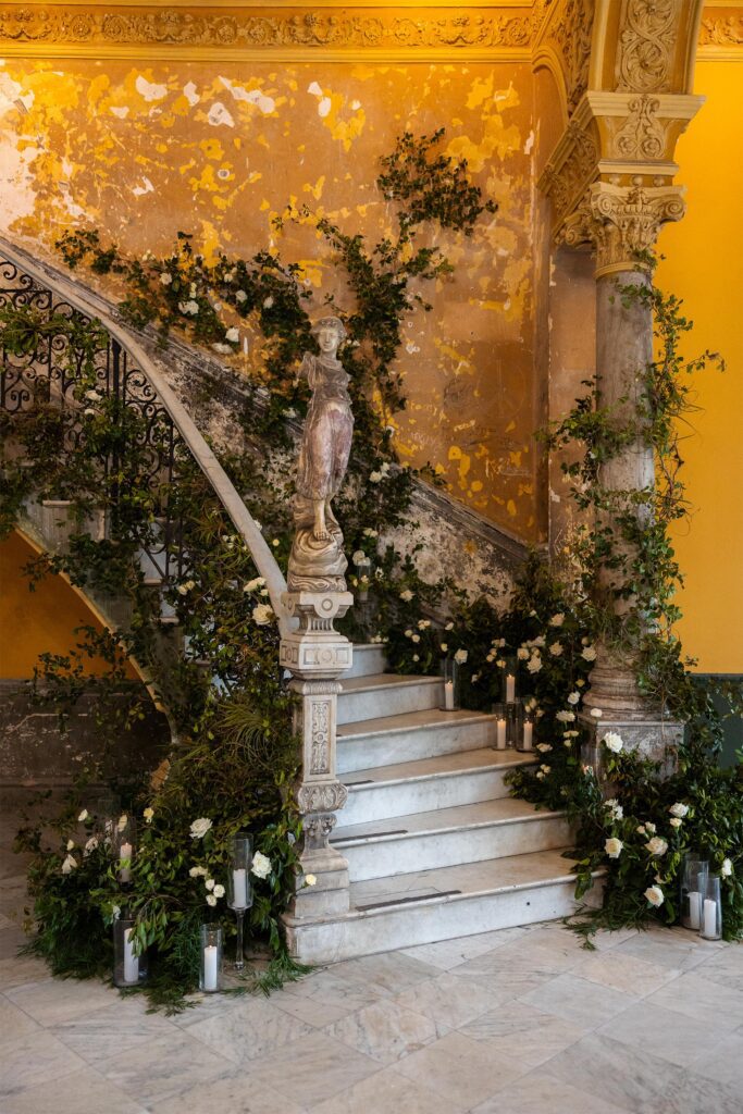 La escalera principal de La Guarida decorada con greenery y flores blancas para una boda de destino en La Habana, Cuba.