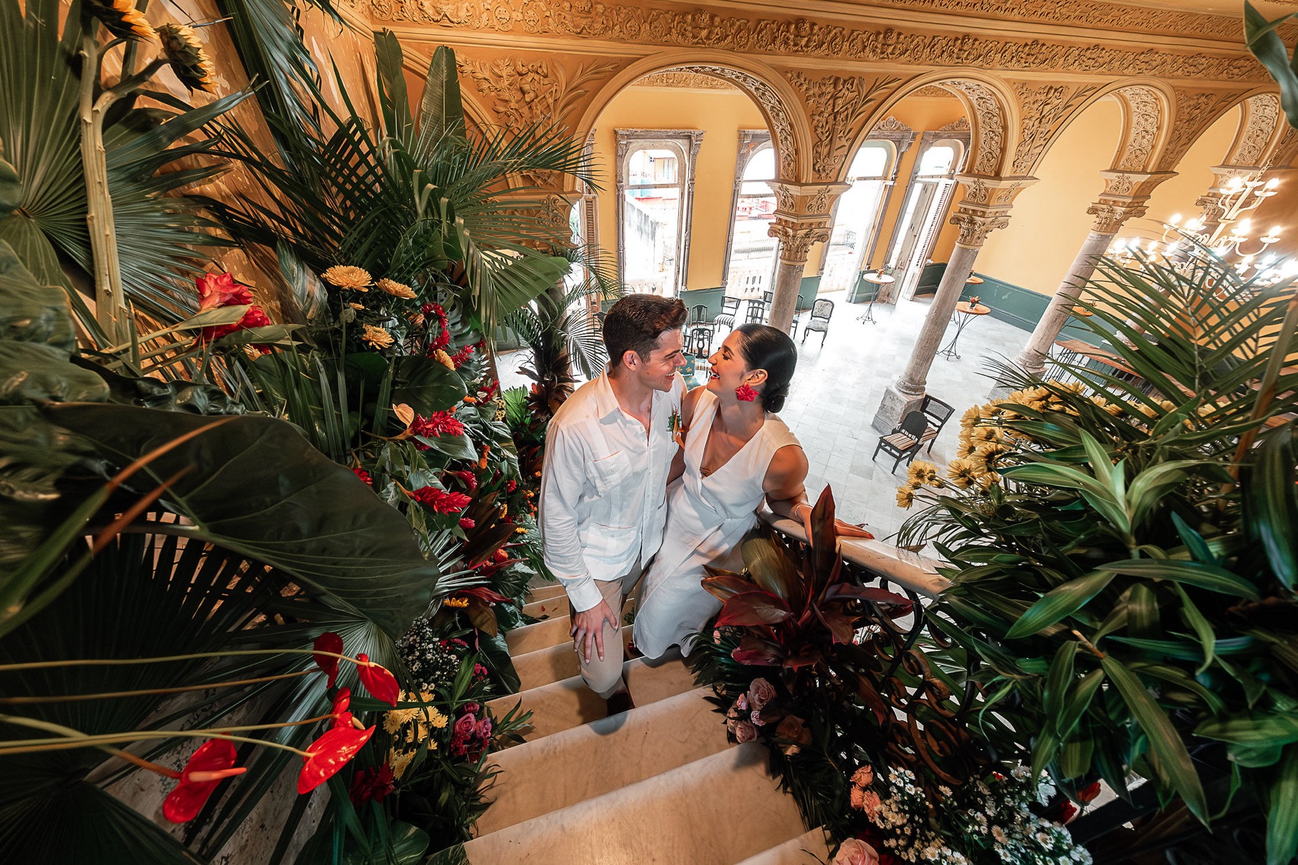 Vista aérea del salón de La Guarida durante la boda de Amanda y Leo, con la pareja posando en la icónica escalera decorada con flores.