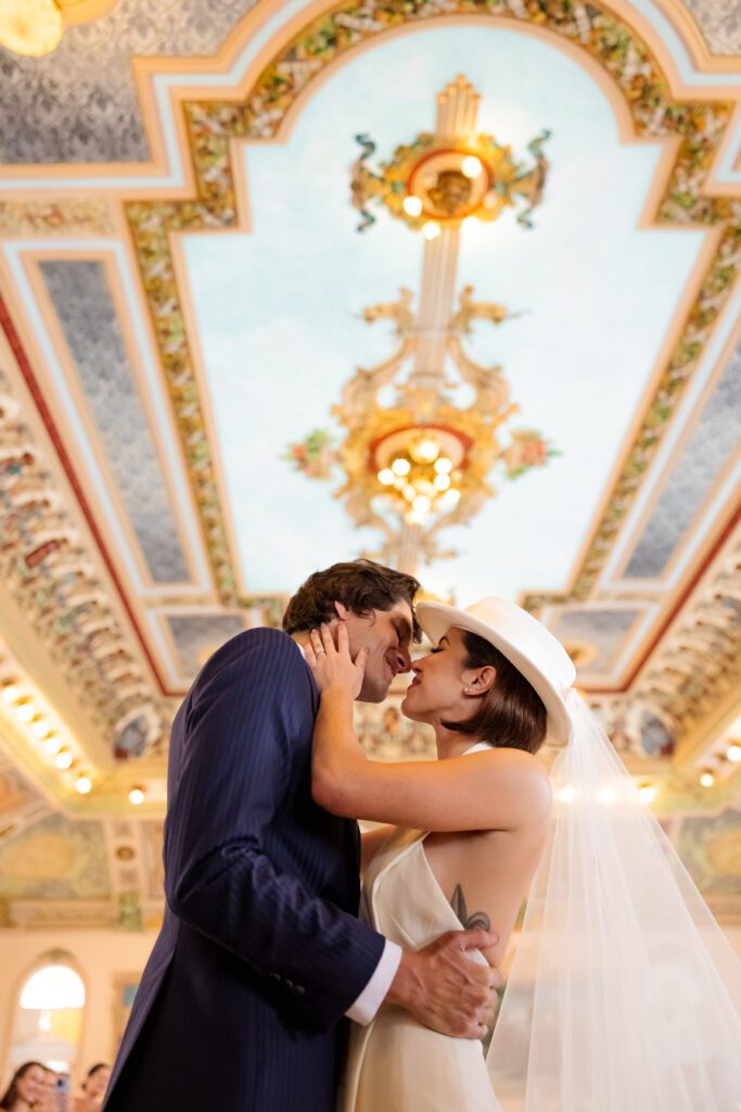 Beso de los novios bajo el techo histórico del Palacio de los Matrimonios en La Habana, Cuba